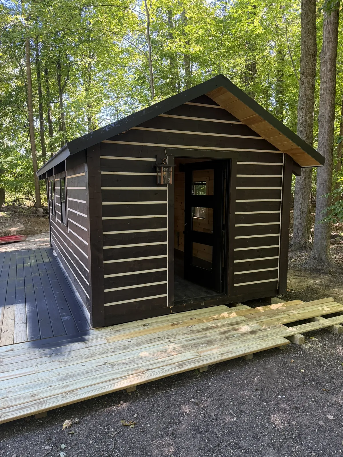 Orana cabin front gable with the door open, in a wooded lot